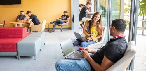 Students talking and working in RIC building lobby